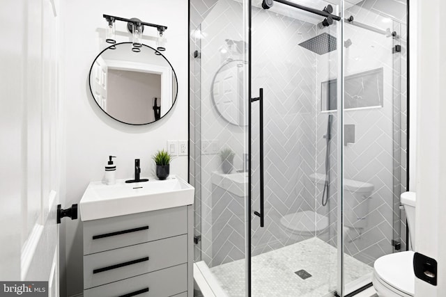 bathroom featuring a shower with door, vanity, and toilet