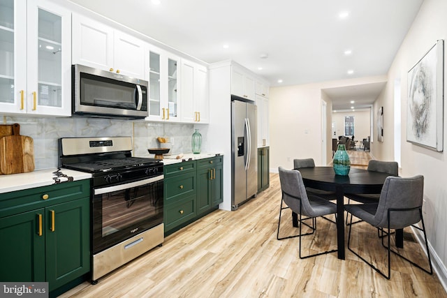 kitchen featuring decorative backsplash, light wood-type flooring, stainless steel appliances, green cabinetry, and white cabinets