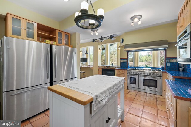 12330 Potomac View Rd, Newburg, MD 20664 - kitchen with appliances with stainless steel finishes, exhaust hood, tasteful backsplash, light tile patterned floors, and glass insert cabinets