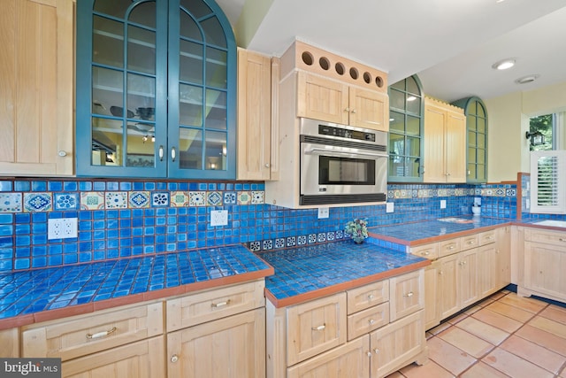 12330 Potomac View Rd, Newburg, MD 20664 - kitchen featuring light brown cabinets, stainless steel oven, decorative backsplash, light tile patterned floors, and glass insert cabinets