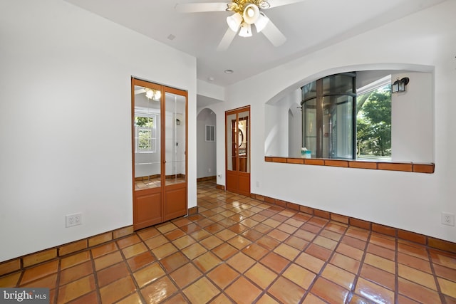 tiled empty room with plenty of natural light and ceiling fan