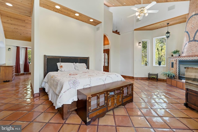 tiled bedroom with ceiling fan, wooden ceiling, high vaulted ceiling, and a tiled fireplace