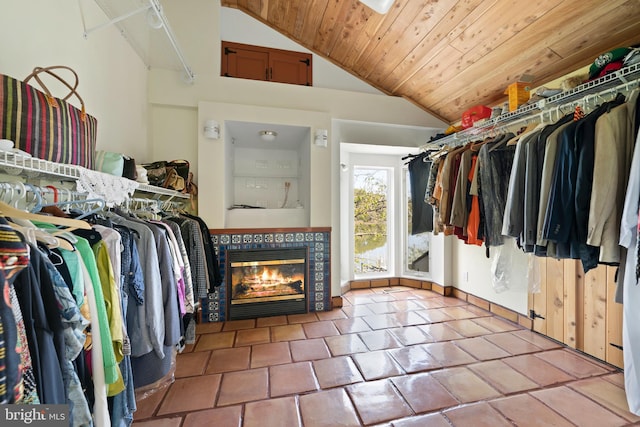 walk in closet with light tile patterned flooring, a tiled fireplace, and vaulted ceiling