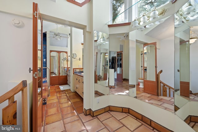 bathroom with ceiling fan, tile patterned flooring, and a towering ceiling