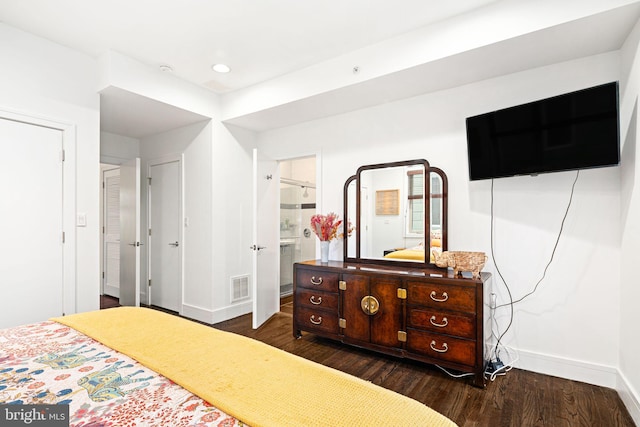 bedroom featuring ensuite bath and dark hardwood / wood-style flooring