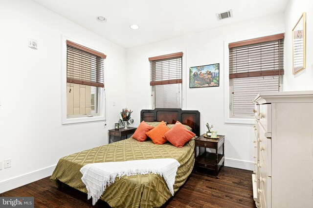 bedroom with multiple windows and dark wood-type flooring