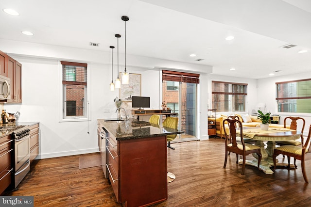 kitchen featuring gas range, sink, hanging light fixtures, dark hardwood / wood-style flooring, and a kitchen bar