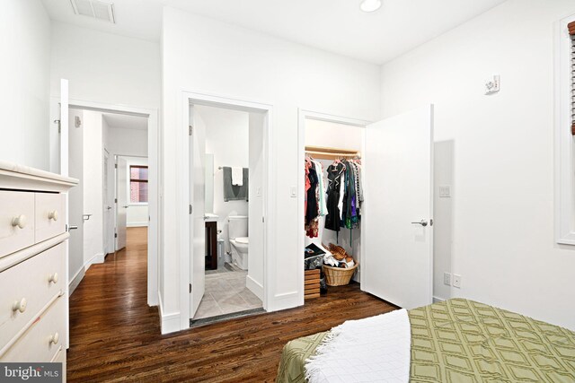 bedroom featuring ensuite bathroom, a spacious closet, dark wood-type flooring, and a closet