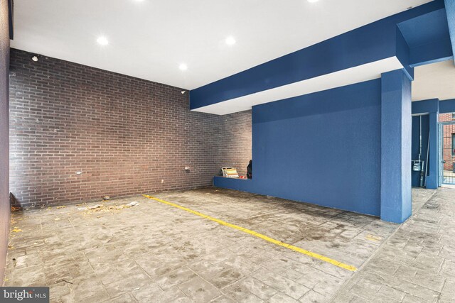 unfurnished living room featuring brick wall