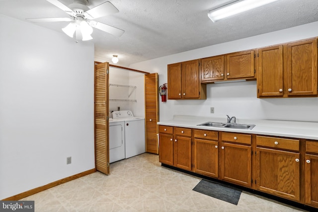 kitchen featuring washer and dryer, a textured ceiling, ceiling fan, and sink