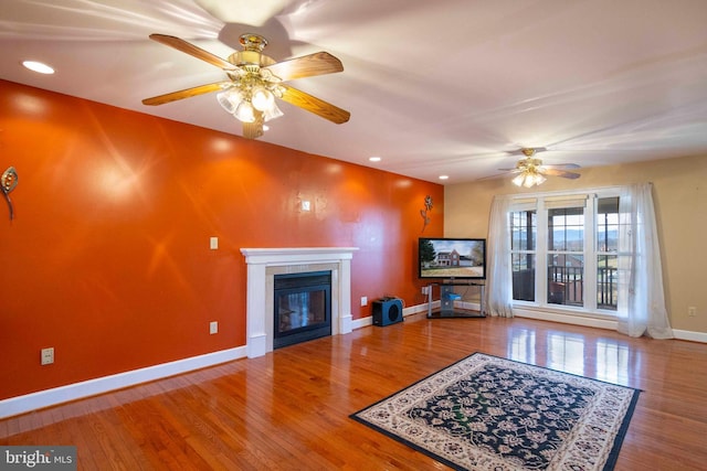 living room with ceiling fan, wood-type flooring, and a fireplace