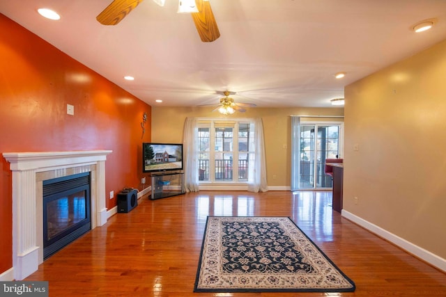 living room with ceiling fan, a fireplace, and light hardwood / wood-style flooring