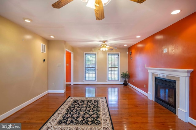 unfurnished living room featuring a tile fireplace, ceiling fan, and wood-type flooring