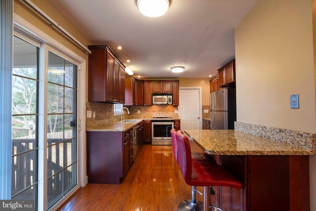 kitchen featuring light stone countertops, sink, dark wood-type flooring, backsplash, and appliances with stainless steel finishes