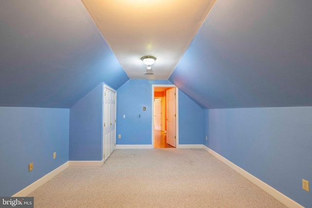 additional living space featuring light carpet and vaulted ceiling