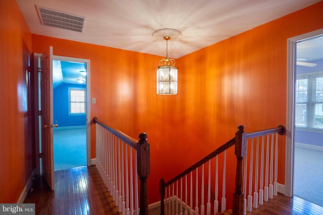 stairway with a chandelier, hardwood / wood-style floors, and lofted ceiling