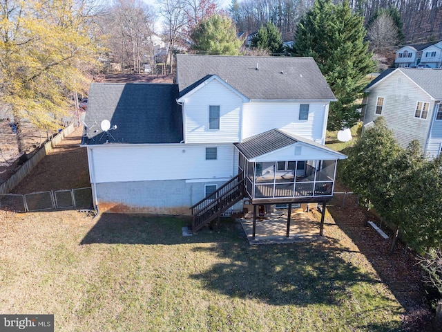 rear view of property with a sunroom, a deck, and a yard