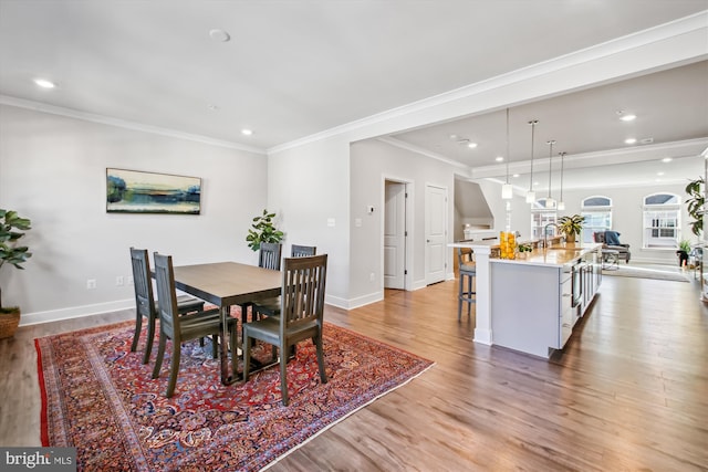 dining space featuring sink, hardwood / wood-style floors, and ornamental molding