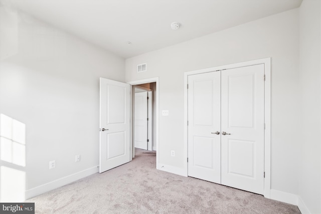 unfurnished bedroom featuring light colored carpet and a closet