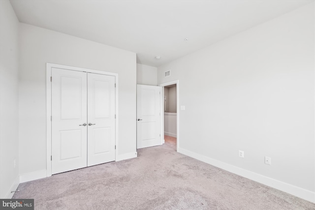 unfurnished bedroom with light colored carpet and a closet