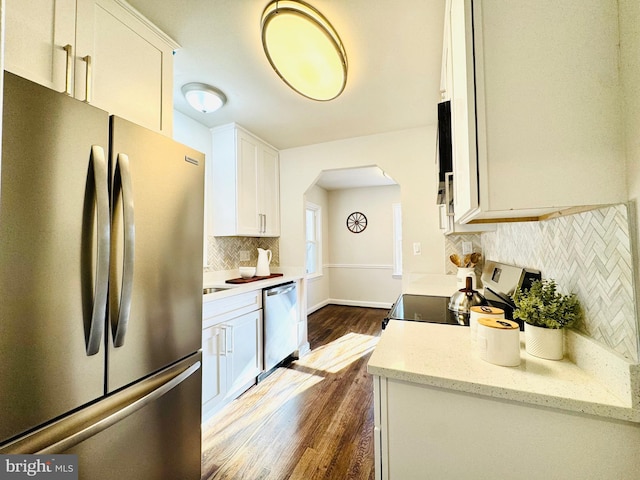 kitchen with backsplash, dark hardwood / wood-style floors, light stone countertops, appliances with stainless steel finishes, and white cabinetry