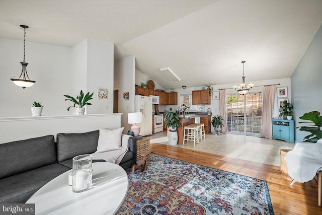 living room featuring lofted ceiling, light wood-type flooring, and an inviting chandelier