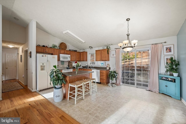 kitchen with a center island, light hardwood / wood-style flooring, lofted ceiling, white appliances, and a breakfast bar