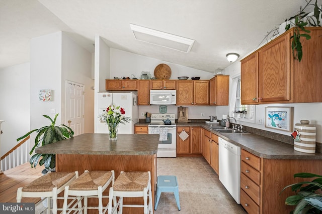 kitchen with sink, lofted ceiling, white appliances, a breakfast bar area, and a kitchen island