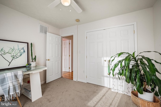 interior space with ceiling fan and light colored carpet