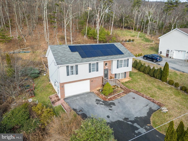 raised ranch featuring a front yard, solar panels, and a garage