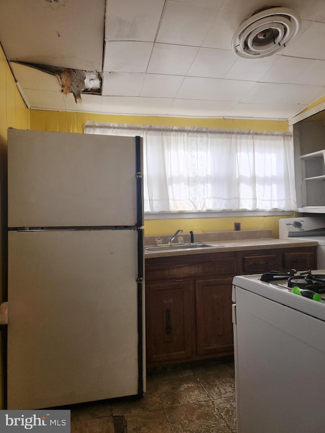 kitchen featuring white range with gas stovetop, sink, and fridge