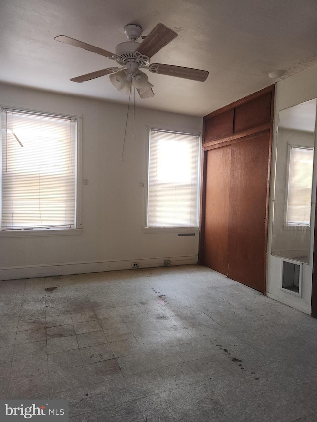 unfurnished bedroom with ceiling fan and a closet