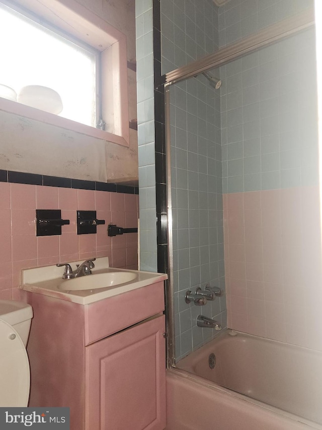 full bathroom with toilet, decorative backsplash, vanity, tile walls, and tiled shower / bath