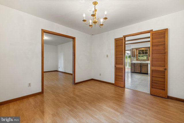 spare room with sink, light hardwood / wood-style flooring, and a notable chandelier