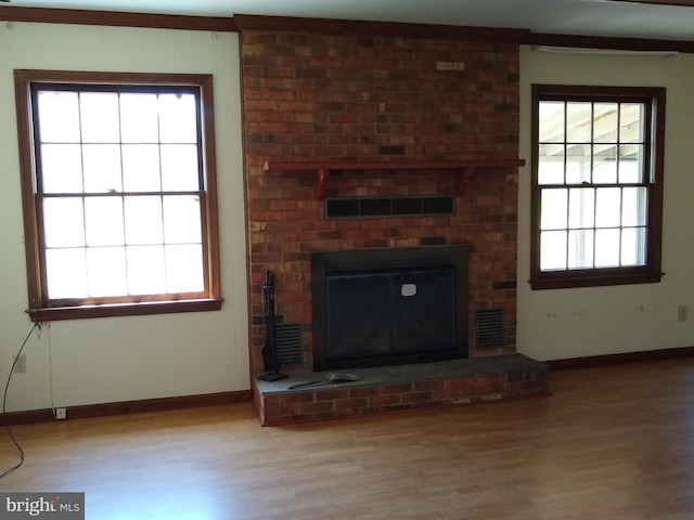 unfurnished living room with plenty of natural light, light hardwood / wood-style floors, and a brick fireplace