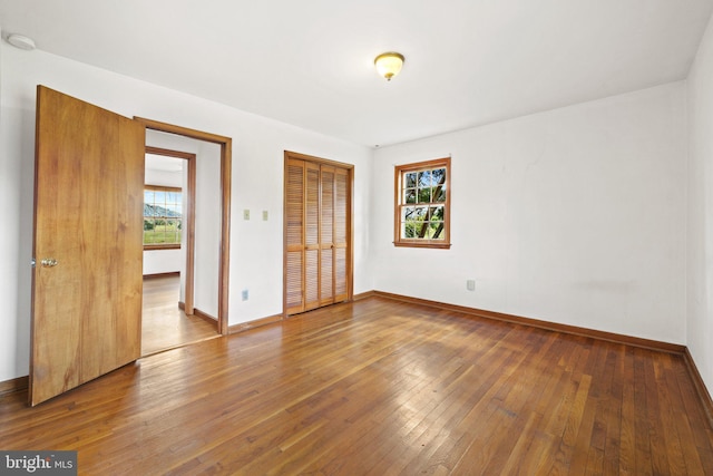 unfurnished bedroom featuring hardwood / wood-style flooring and multiple windows