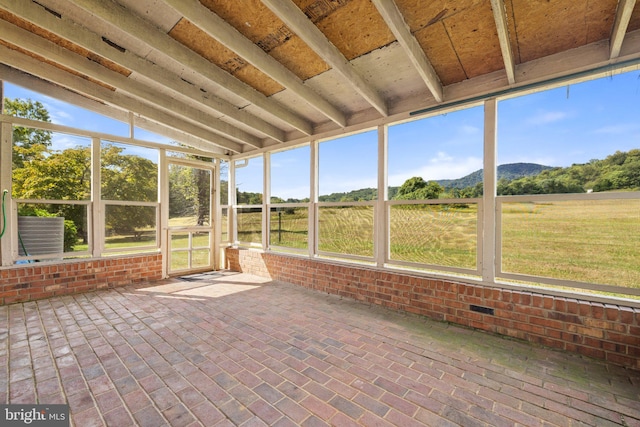 unfurnished sunroom with a rural view, vaulted ceiling, and plenty of natural light