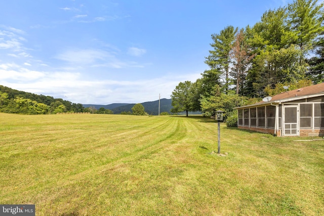 view of yard featuring a sunroom and a mountain view