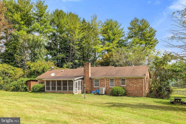 rear view of house featuring a sunroom, a yard, and cooling unit