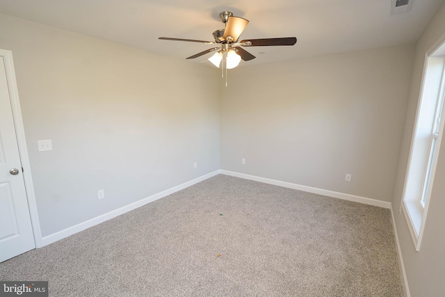 carpeted spare room featuring ceiling fan and a wealth of natural light