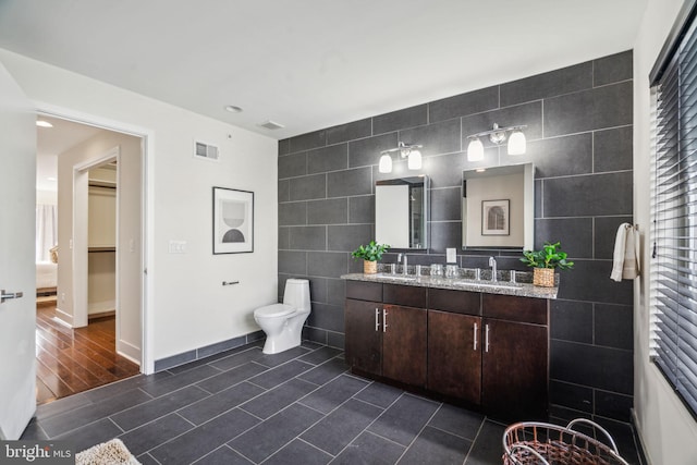 bathroom featuring tile walls, wood-type flooring, vanity, and toilet