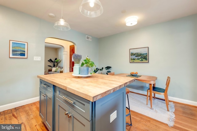 kitchen with pendant lighting, wooden counters, a center island, and a breakfast bar area