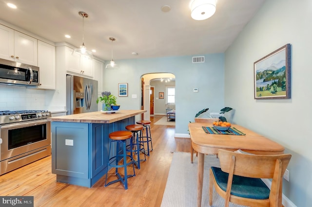 kitchen featuring white cabinetry, hanging light fixtures, stainless steel appliances, and a kitchen island