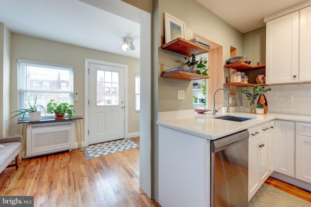 kitchen featuring sink, white cabinetry, tasteful backsplash, light hardwood / wood-style flooring, and stainless steel dishwasher