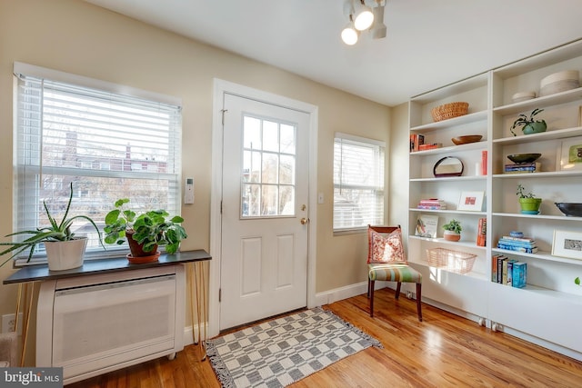 doorway with heating unit and light hardwood / wood-style flooring