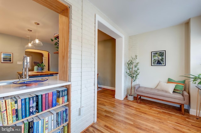 hallway featuring brick wall and light wood-type flooring