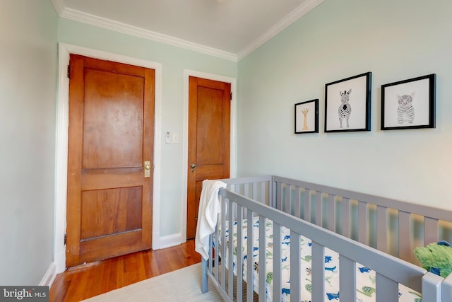 bedroom featuring crown molding, a crib, and hardwood / wood-style flooring