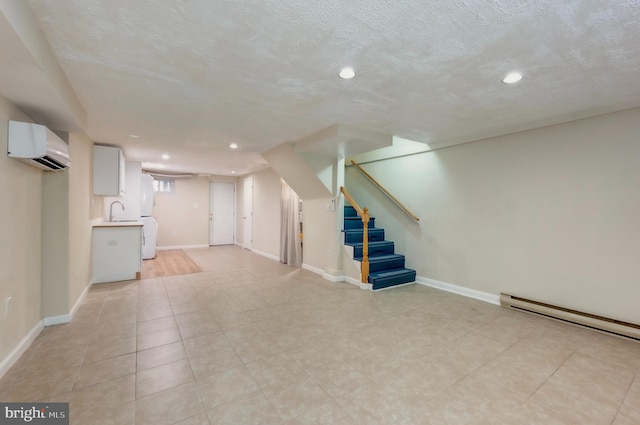 basement with a wall mounted AC, sink, a textured ceiling, and a baseboard heating unit