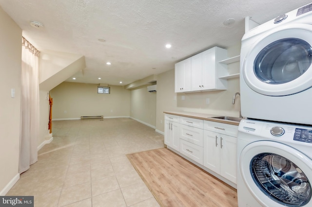 laundry room featuring stacked washer / dryer, sink, a wall mounted air conditioner, and a textured ceiling