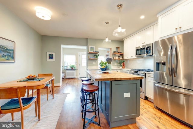 kitchen with pendant lighting, stainless steel appliances, wooden counters, and white cabinets